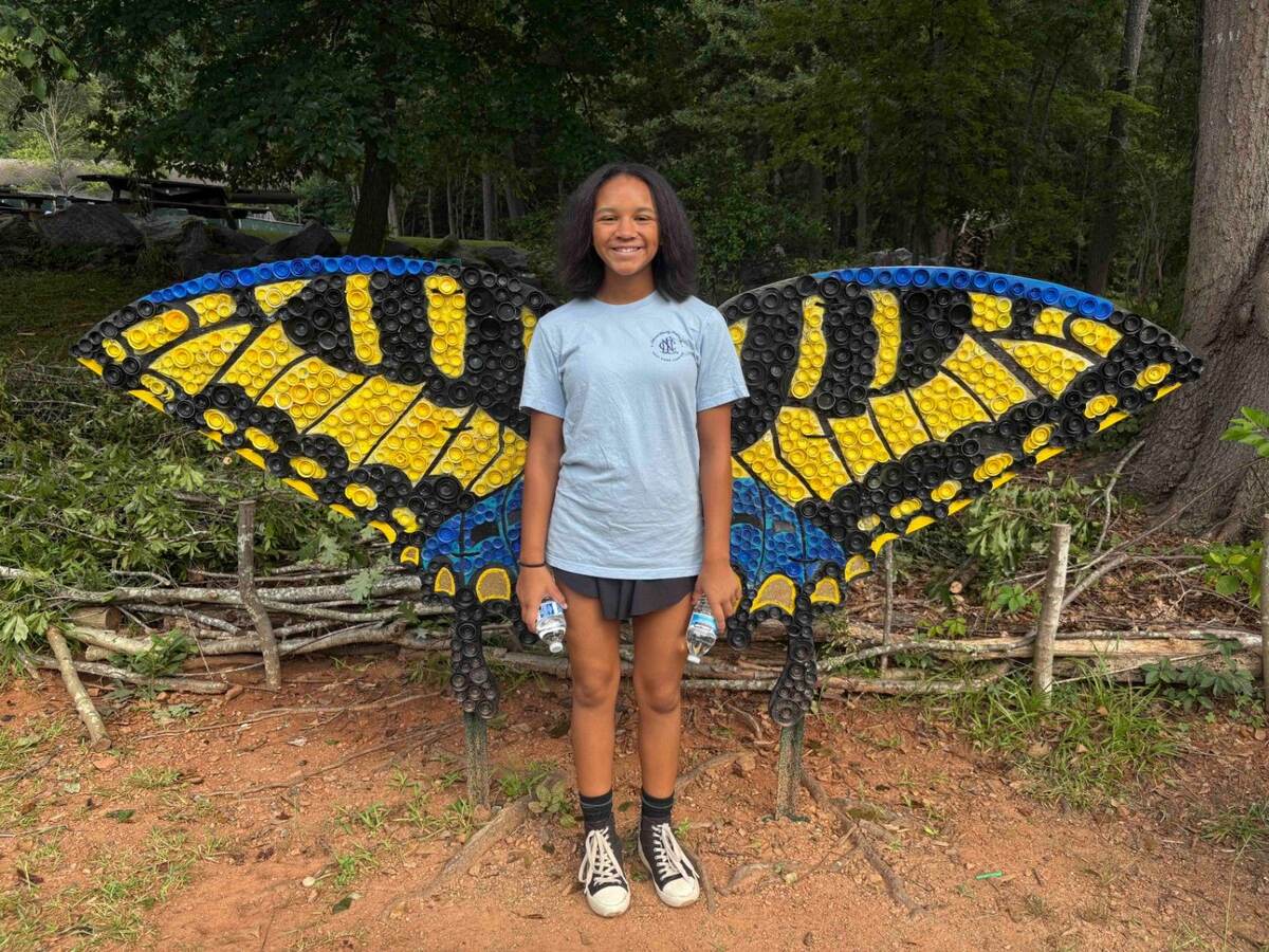 Abby smiling in front of a large butterfly sculpture at the Chattahoochee Nature Center